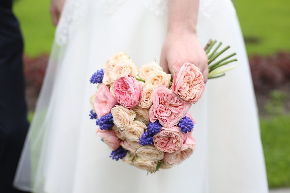 A collection of fresh peony bouquets featuring shades of pink, white, and deep red, wrapped in brown craft paper and arranged on the floor. The flowers display lush, full petals with some buds still c